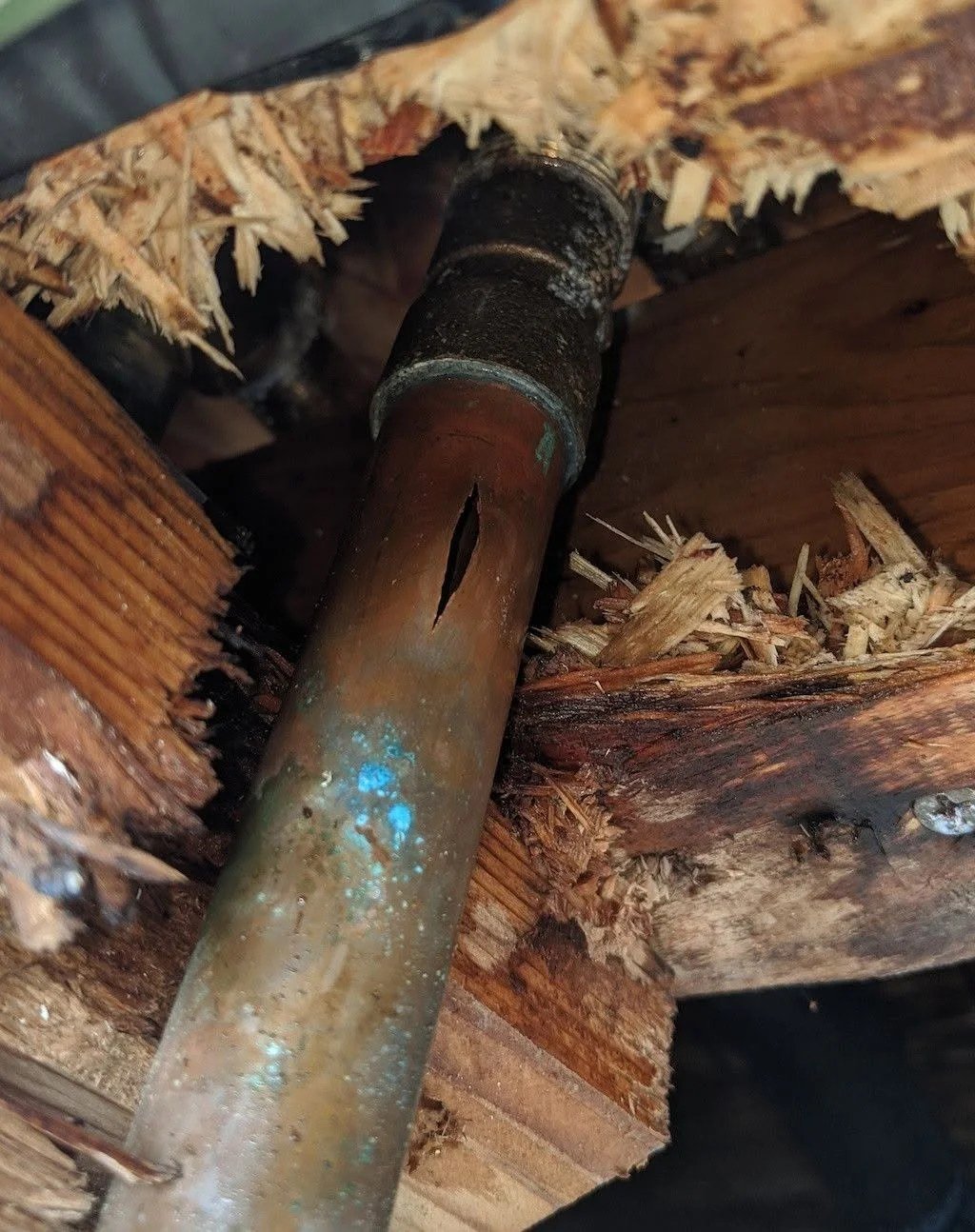 Close-up of a corroded copper supply pipe with a split along its length